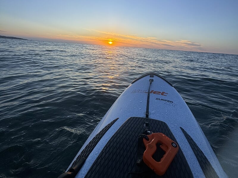 Planche de surf électrique voguant sur l'océan devant un coucher de soleil