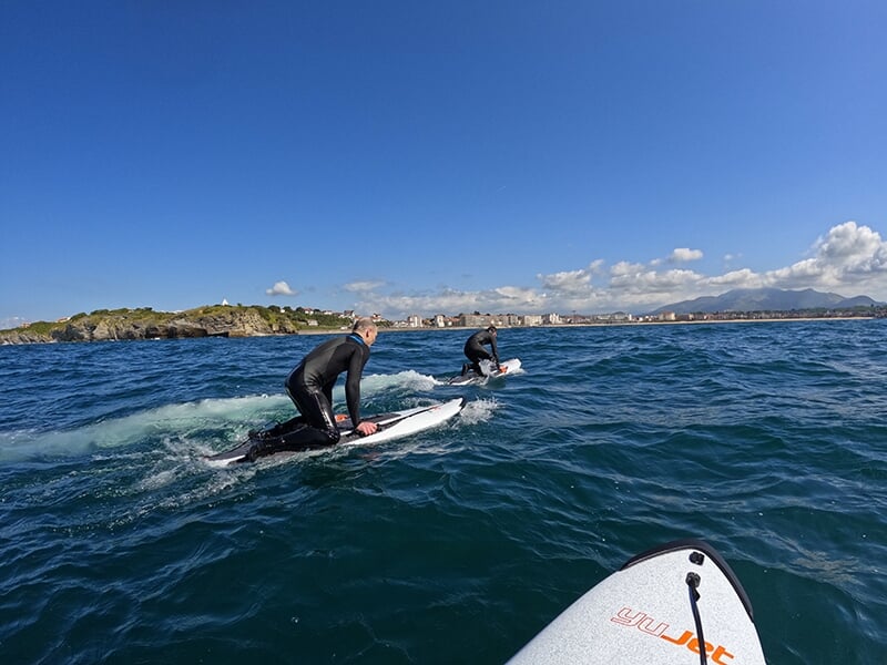 Surfeurs à genoux sur une planche de surf électrique avec la côte Atlantique en toile de fond