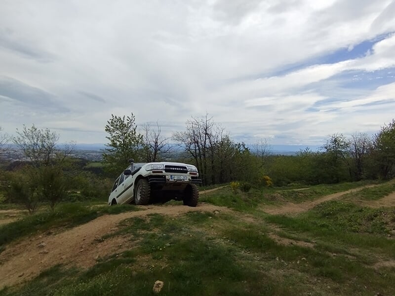 Un 4x4 franchit un obstacle sur une piste située en plein au milieu d'une forêt ardéchoise