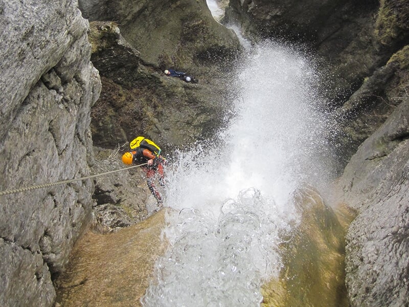 Un canyoneur fait une descente en rappel périlleuse le long d'une cascade à fort débit