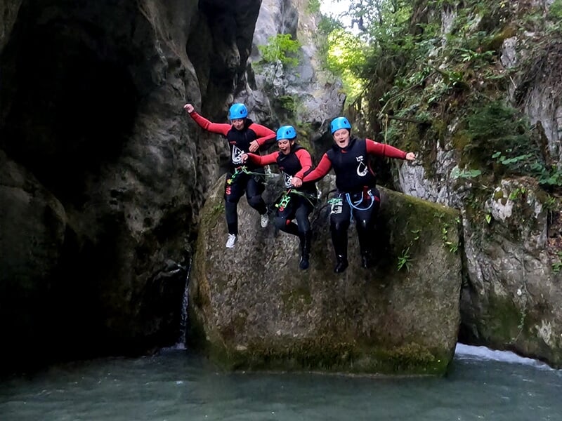 Un groupe de canyoneurs sautent depuis un rocher dans l'eau glacée d'un torrent
