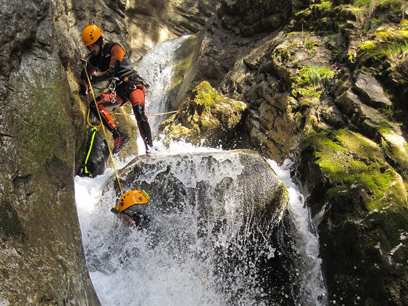 Deux canyoneurs entament la descente technique d'une cascade particulièrement arrosée lors d'une sortie canyoning