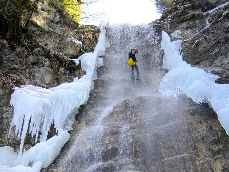 Un canyoneur pratique l'ice canyoning dans un canyon accessible toute l'année