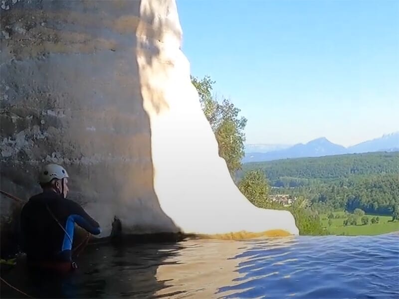 Un canyoneur vêtu d'une combinaison en néoprène admire les beaux paysages du Bugey depuis un belvédère