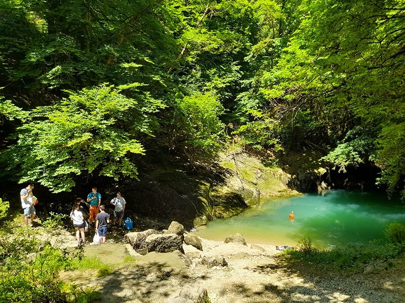 Un groupe de canyoneurs devant une source d'eau sortant tout droit d'un réseau karstique