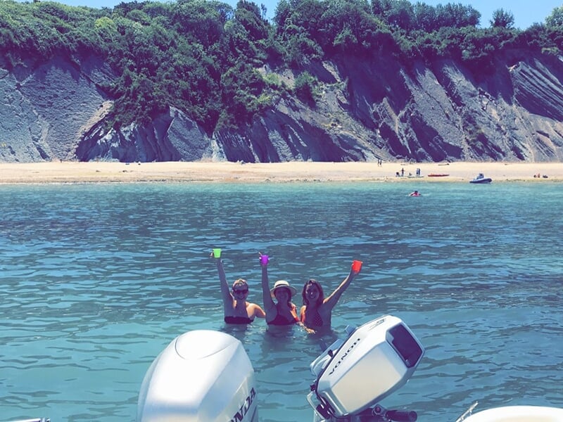 Femmes en train de prendre l'apéritif dans l'eau avec une plage paradisiaque en arrière-plan