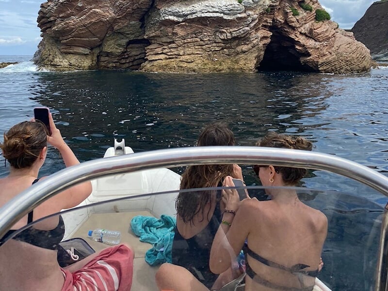 Groupe de femmes en maillot de bains photographiant à bord d'un bateau un rocher près d'Hendaye
