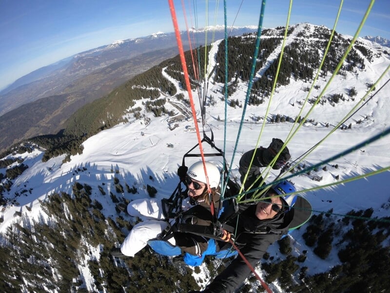 Deux personnes en parapente au dessus des montagnes en hiver