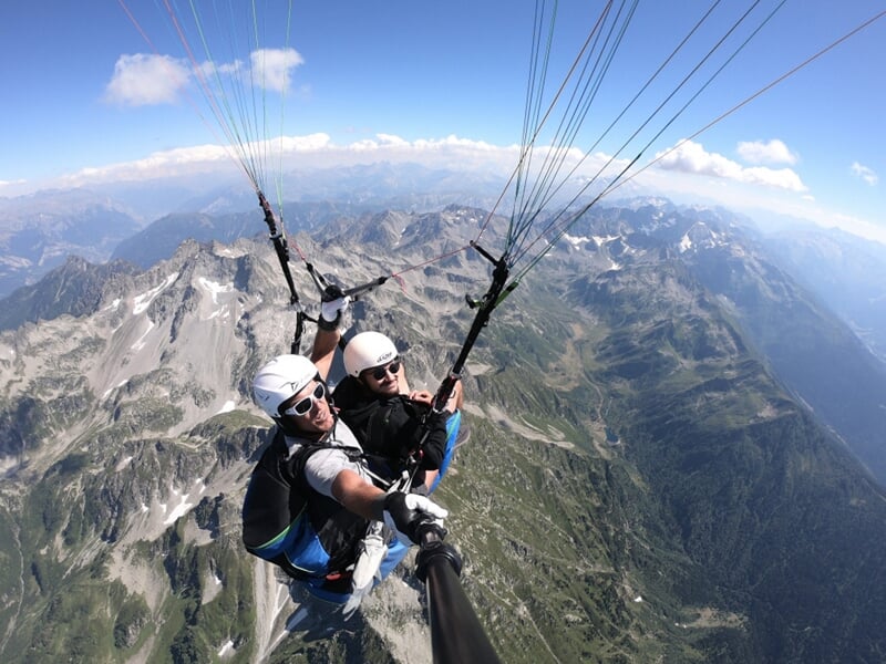 Deux personnes en parapente au dessus des montagnes