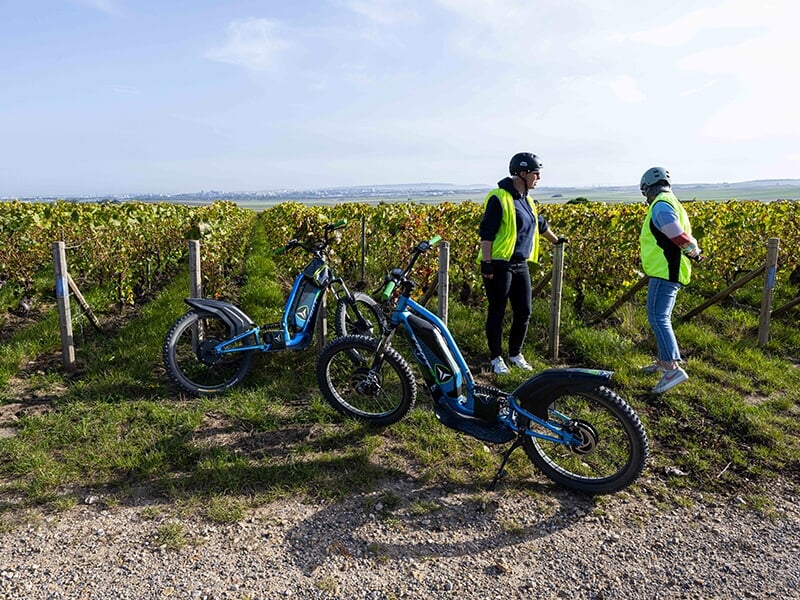 Des touristes visitent le vignoble de Champagne en trottinette électrique.