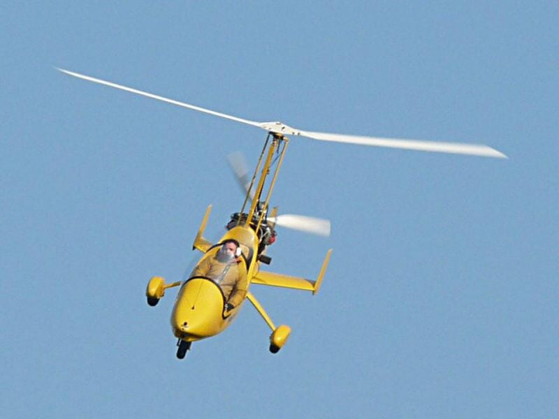 ULM jaune en vol vu de face, avec un pilote visible dans le cockpit, ciel clair en arrière-plan.