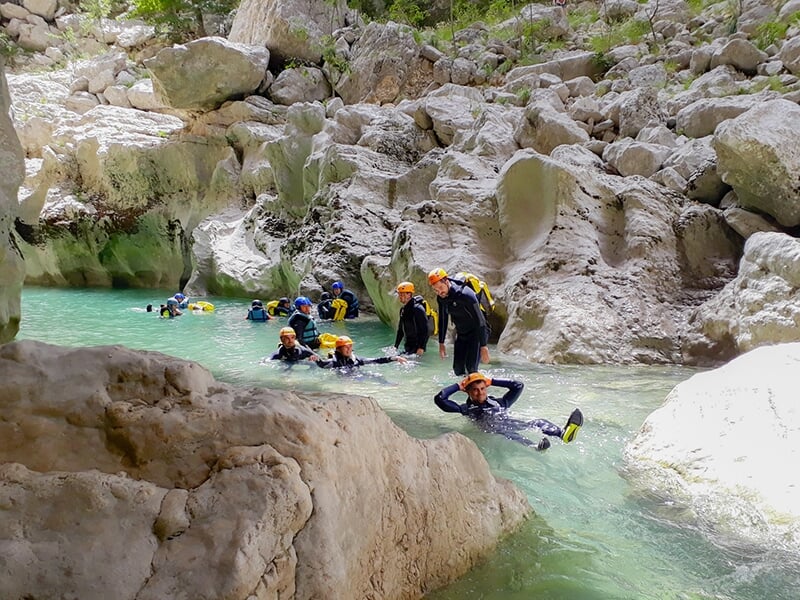 Un groupe de canyoneurs vêtus de combinaisons néoprènes se laissent porter par le courant du Verdon