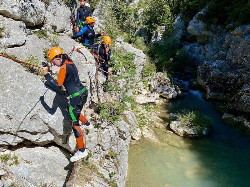 Un groupe de randonneurs longuent une paroi rocheuse en étant encordés au cours d'une session de canyoning