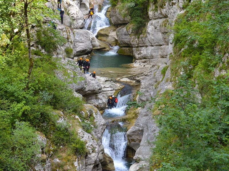 Vue de loin d'un canyon creusé par un torrent alors qu'une randonné aquatique a lieu au fond des gorges