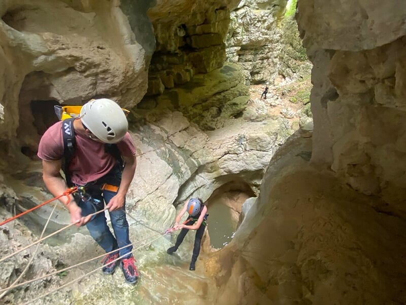 Deux grimpeurs encordés réalisent une descente en rappel dans un canyon escapé
