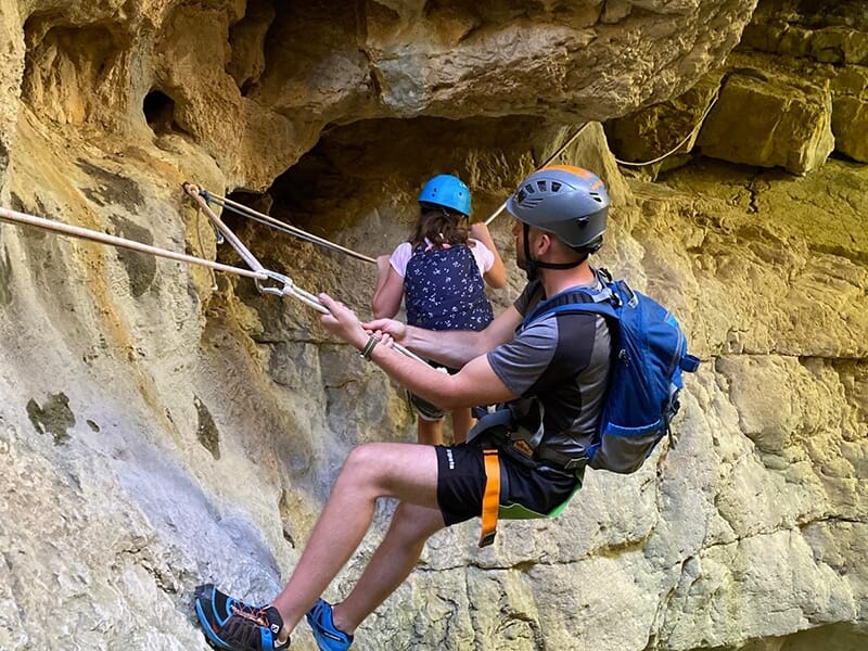 Des touristes équipés de matériel d'escalade longent une paroi rocheuse dans le Verdon