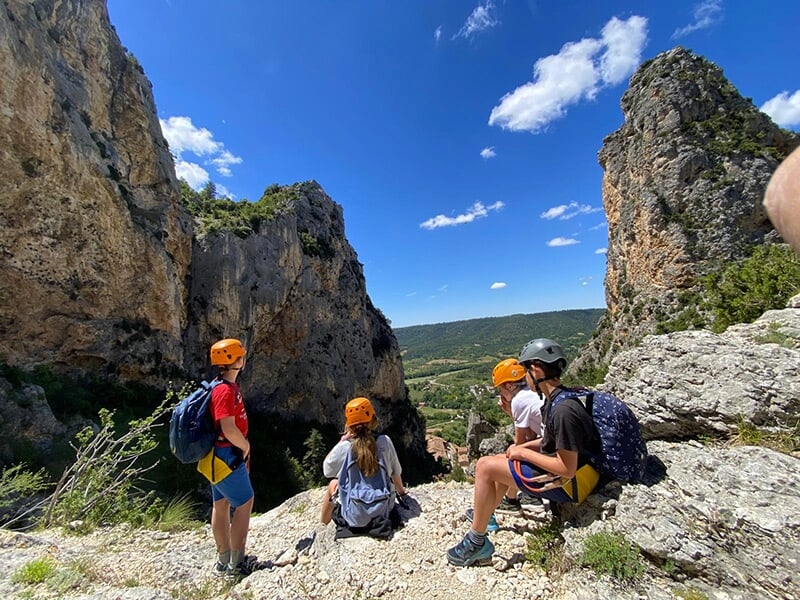 Groupe de grimpeurs portant des casques assis sur des rochers avec des pitons rochaux en arrière-plan