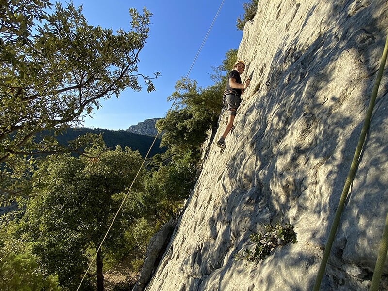 Un homme apprend les fondamentaux de l'escalade sur une paroi rocheuse calcaire