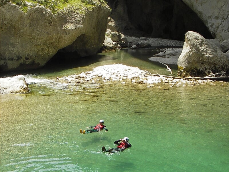 Des canyoneurs profitent d'un moment de repos dans les eaux limpides d'un torrent de montagne.