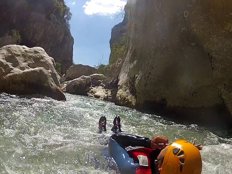 Un canyoneur descend une rivière à haut débit dans un canyon encaissé.