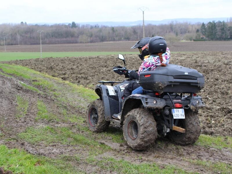 Un pilote de quad et son passager parcourent un chemin au milieu des champs