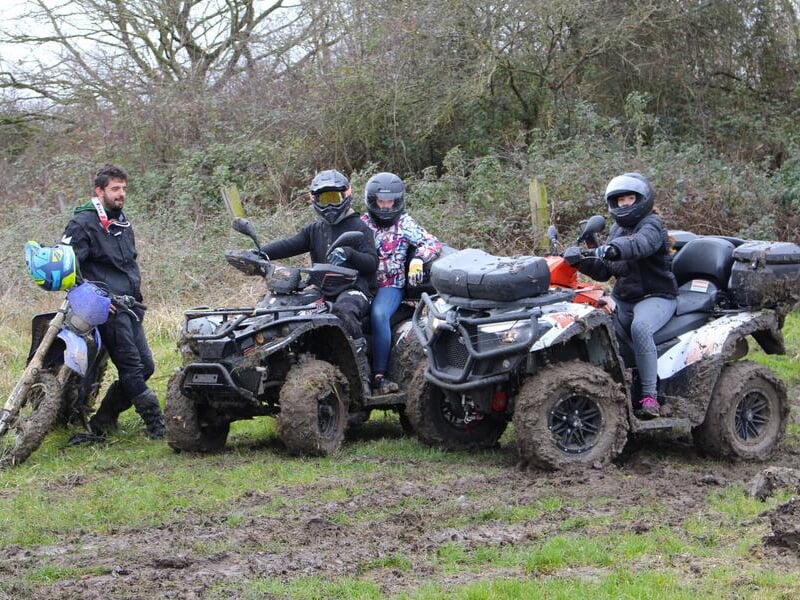 Un groupe de randonneurs en quad à l'arrêt près d'une moto sur un chemin de terre en pleine campagne.