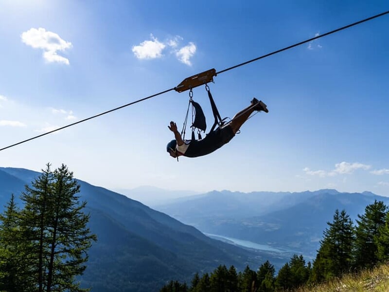 Un homme tend les bras comme s'il volait alors qu'il descend une tyrolienne géante dans les Hautes-Alpes
