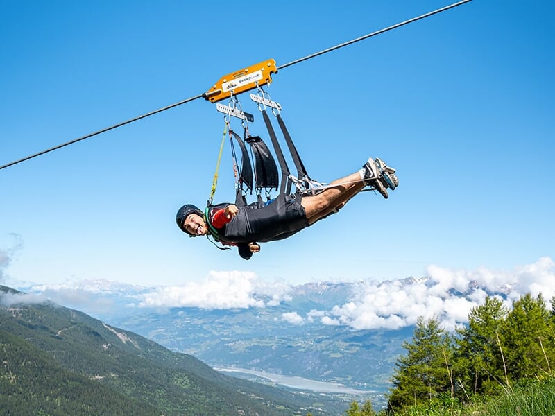 Un touriste pose pour la photo alors qu'il entame une descente en tyrolienne avec le lac de Serre-Ponçon en arrière-plan