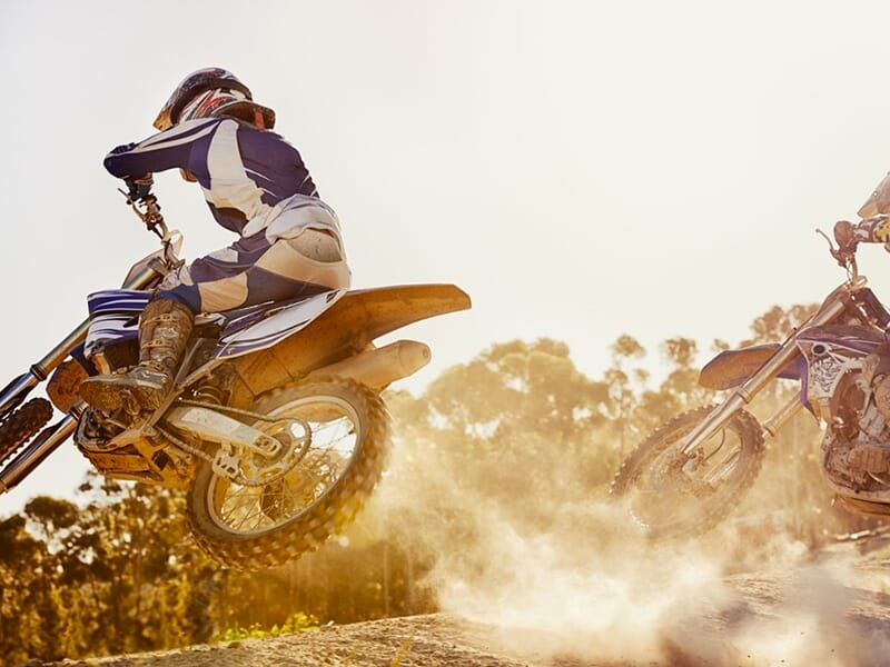 Un pilote de moto tout-terrain décolle du sol sur le terrain de terre d'un circuit de motocross