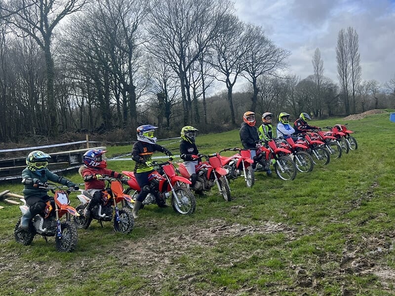 Huit jeunes pilotes de motocross sur leur moto suivent un cours de conduite.