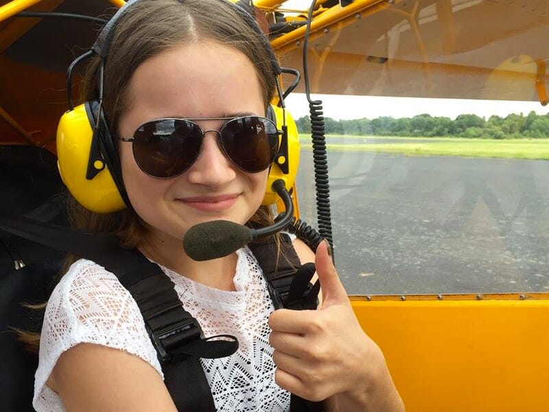 Une jeune fille portant un casque radio tend le pouce en signe de satisfaction dans un avion