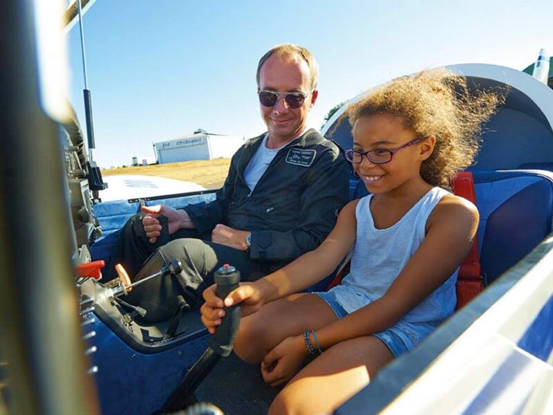 Une jeune fille assiste dans le cockpit d'une Pioneer 200 avec un pilote instructeur