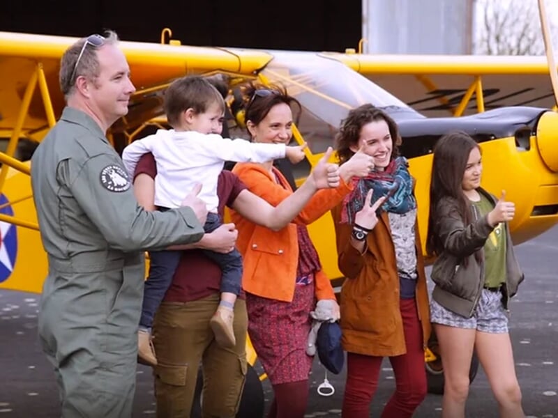 Une famille pose avec le pilote devant un avion de tourisme avant un baptême de l'air à Saumur