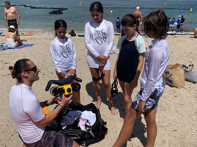 Un moniteur de plongée explique à des enfants comment utiliser un scooter sous-marin