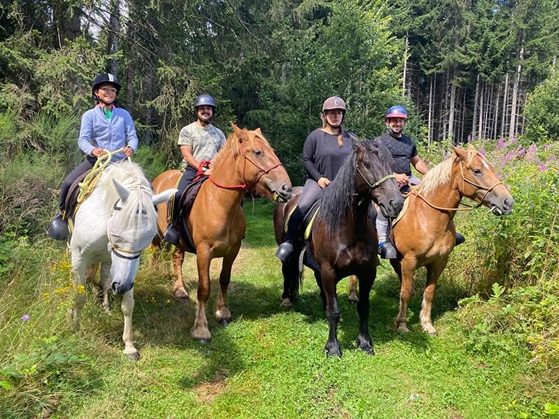 Des cavaliers portant une bombe d'équitation en pleine forêt