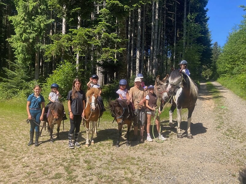 Un groupe de randonneurs à cheval posent pour la photo sur un sentier forestier