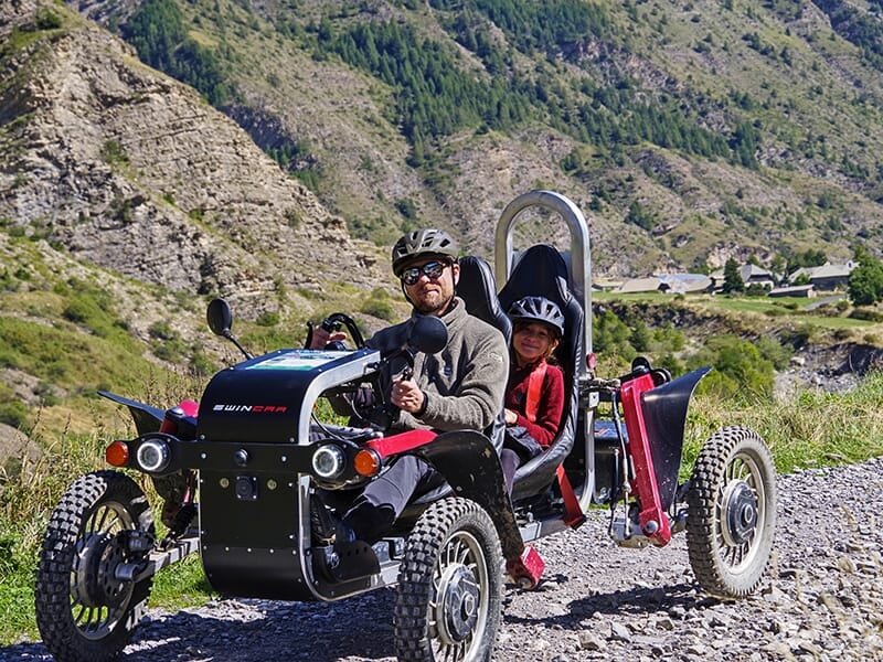 Un homme au volant d'un swincar promène sa fille sur les pistes des Alpes du Sud