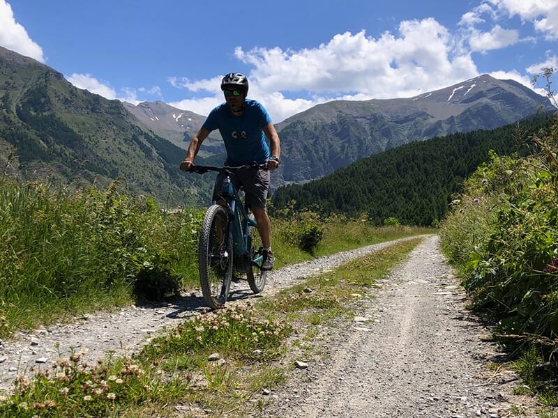 Un homme en VTT gravit un sentier escarpé en plein coeur des Alpes du Sud