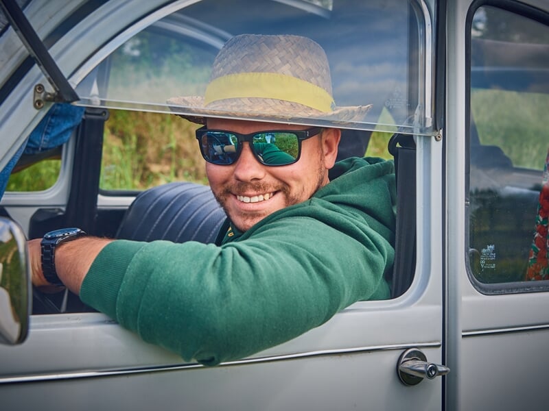 Homme souriant au volant d'une 2CV