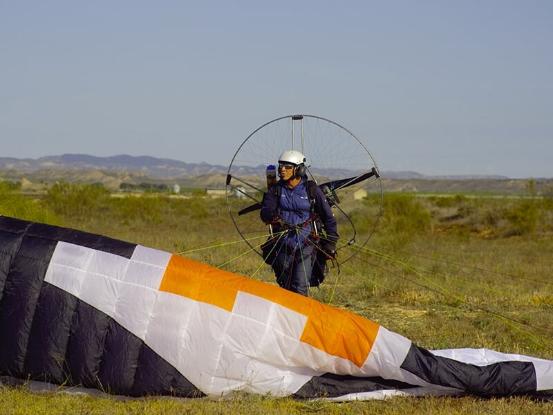 Un pilote de paramoteur dresse sa voile sur une aire de décollage d'ULM