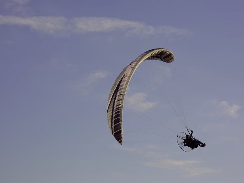 Un pilote de paramoteur entame un virage à forte inclinaison dans les airs