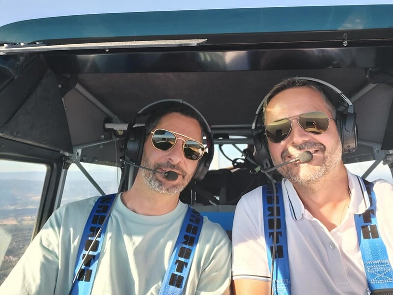 Un pilote instructeur et un stagiaire dans le cockpit d'un ULM casque radio sur la tête lors d'un vol d'initiation  
