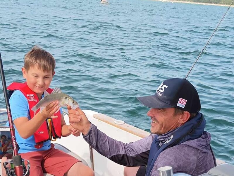 Enfant sur un bateau ayant pêché un poisson