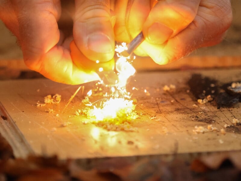 Mains allumant un feu avec un briquet, produisant des étincelles.