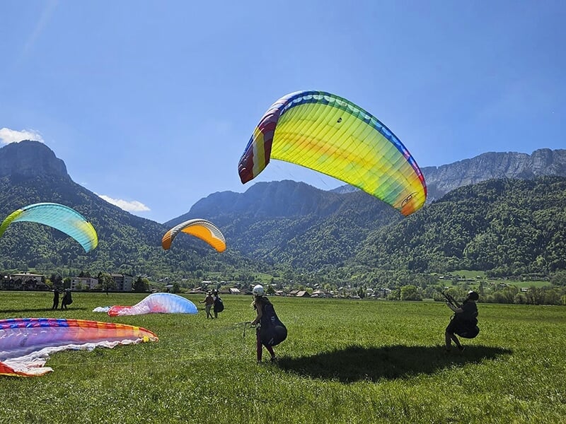 Des stagiaires d'une école de parapente font des exercices pour gonfler leur voile sur la pente école d'un centre de loisirs près d'Annecy