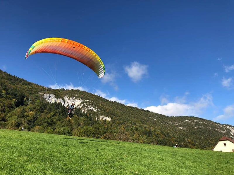 Un paraprente s'envole depuis la piste école d'un centre de parapente de Haute-Savoie