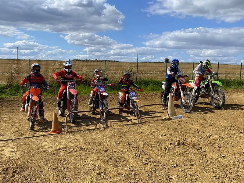 Un groupe de jeunes motards lors d'une session de motocross sur une piste de terre