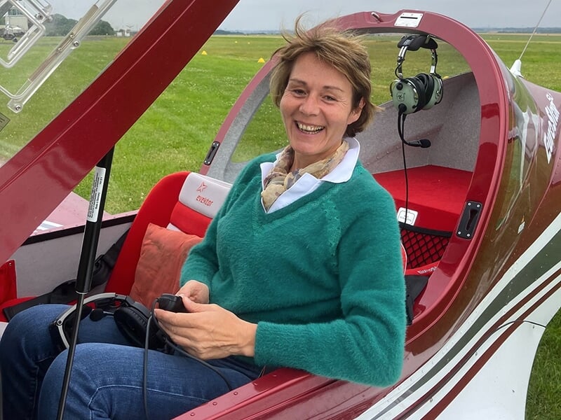 Une femme souriante dans le cockpit d'un avion ULM avant un baptême de l'air