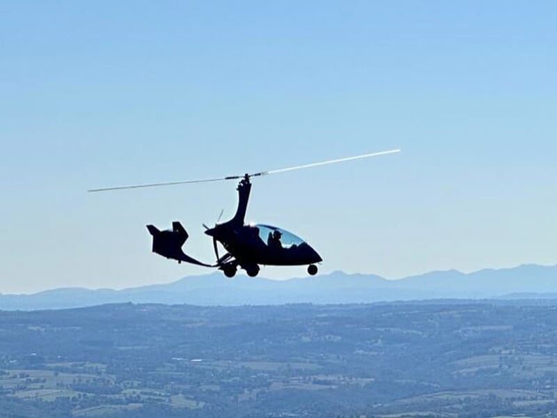 Un autogire en plein vol au-dessus d'une vaste plaine par un temps clair