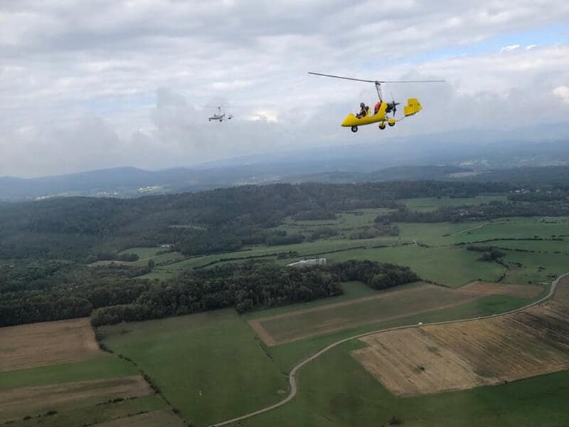 Deux autogires survolent une plaine agricole par un temps couvert